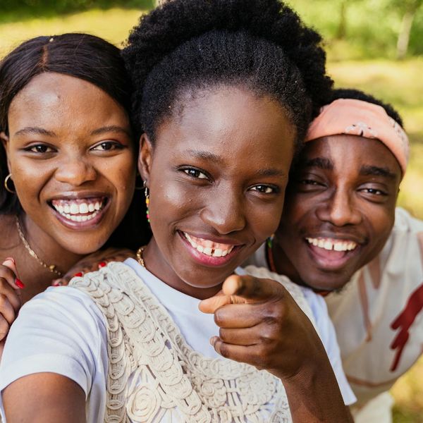 A diverse group of people smiling during a light yoga session outdoors.