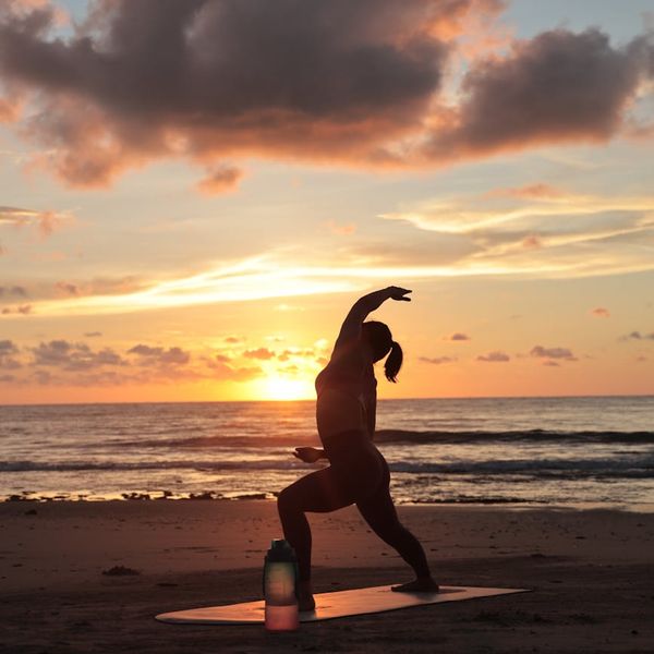 Silhouette of a person in a warrior yoga pose during a beautiful sunrise.
